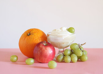 Yogurt with an orange, apple, and grapes.