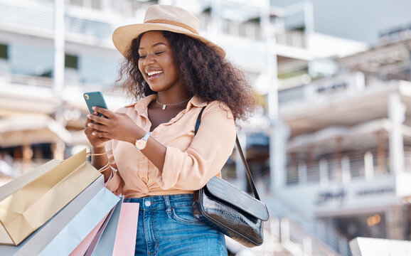 Shopping bag, smartphone and black woman in city with retail sale announcement, newsletter discount code or ecommerce website. Wealth, success customer in urban outdoor using phone for online choice