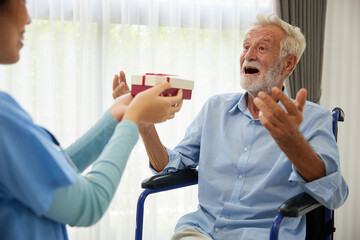 senior man taking a gift box from caregiver for happy birthday