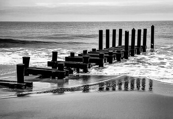 A Pier juts into the Atlantic Ocean off the coast of New Jersey, with the reflection visible as the...