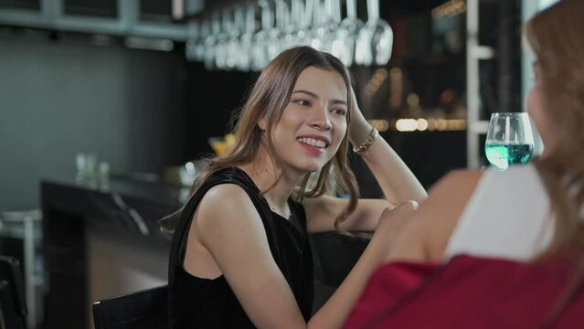 Two beautiful asian female businesswoman lady drink cocktail together and chit chatting about life in a rooftop bar after a long day work
