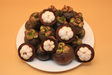 Peeled mangosteen and some pieces are still not cut placed in several dishes