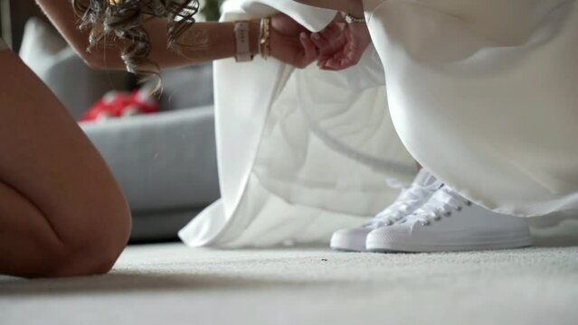 A friend helps a bride with her dress