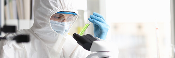 Scientist in protective suit studies toxic poisonous liquids in laboratory