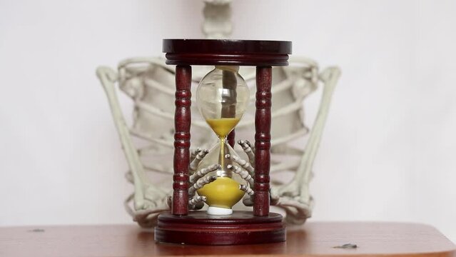 The skeleton holds an hourglass on a white background, time is up, it's time to live