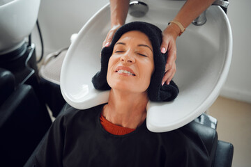 Woman, hairdresser and hair care being relax, with head dry with towel after wash in basin. Salon,...