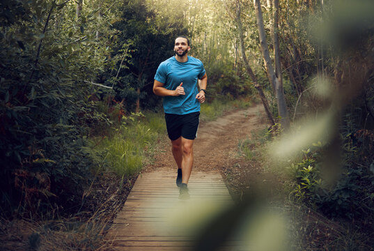 Man, running and fitness on forest path, nature woods bridge or countryside environment for health, wellness or heart health. Smile, happy or sports runner in exercise, training and workout in Canada