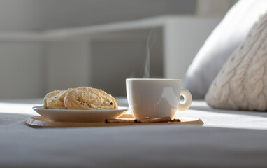 cup of coffee on wooden tray on bed in cozy bedroom