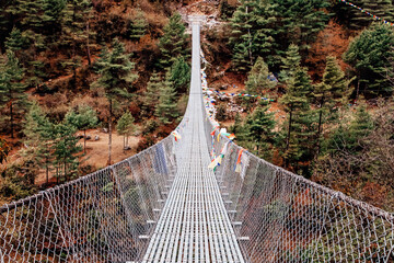 TTrekker crossing metal suspension bridge in Nepal, Himalayas.
