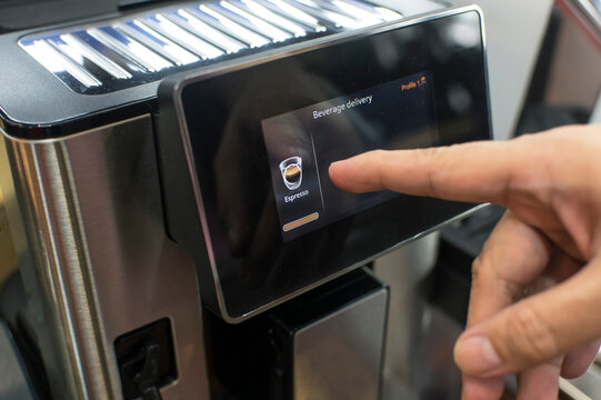 A barista operating a touchscreen coffeemaker, selecting an Espresso.