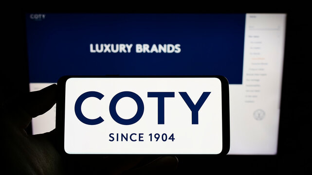 Stuttgart, Germany - 10-03-2022: Person holding smartphone with logo of US beauty company Coty Inc. on screen in front of website. Focus on phone display.