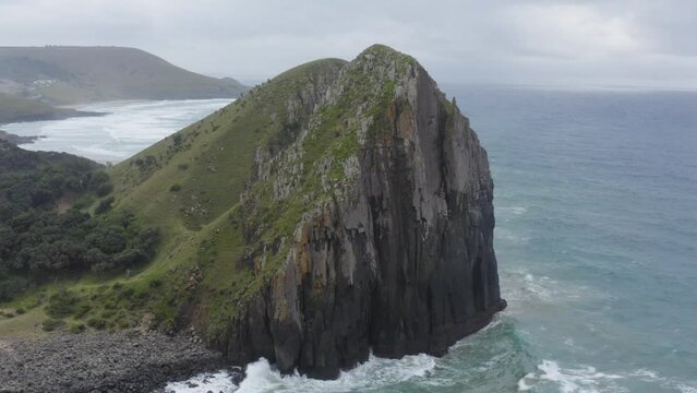 Drone flying towards rocky cliff and green grass rolling hills Transkei, South Africa