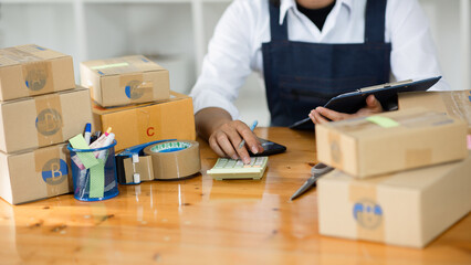 SME entrepreneurs, small business entrepreneurs Online Selling Idea, Young Asian Business Owner work on computers and boxes at home, SME procurement parcel boxes delivered to customers,