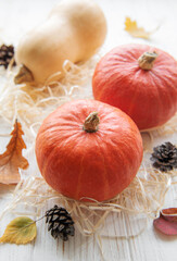 Autumn decorative pumpkins with fall leaves on wooden background.