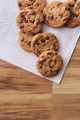 Raisin cookies placed on white paper served on a wooden table.