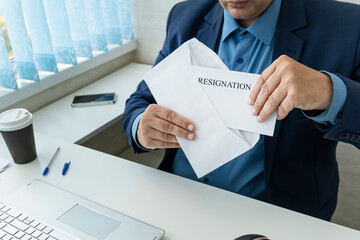 An employee opens a letter of resignation at the workplace. The boss fires employees. businessman...