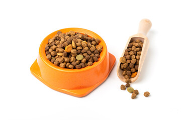 A bowl full of dry pet food, and a scoop full of food on a white background.	