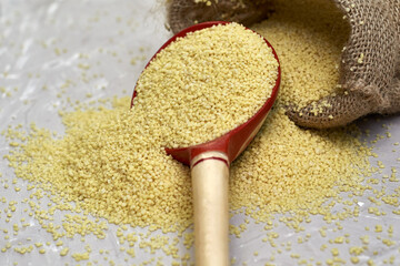 croup couscous spills out of a canvas bag and a wooden spoon on the table
