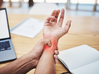 Businessman, wrist pain and injury at desk working, planning and writing in workplace with laptop....