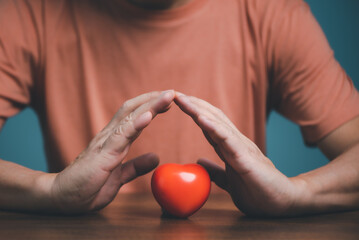 Hands holding and protect red heart for love, health care, organ donation, world heart day, world health day, mindfulness, well being, family insurance concept.