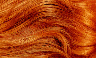 Red hair close-up as a background. Women's long orange hair. Beautifully styled wavy shiny curls....