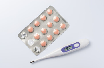 Medical electronic thermometer and tablets on a white background. The concept of diagnosis and treatment of diseases.