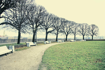 Vintage dull city park landscape with footpath and benches in faded colors.