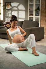 Beautiful pregnant woman practising yoga at home