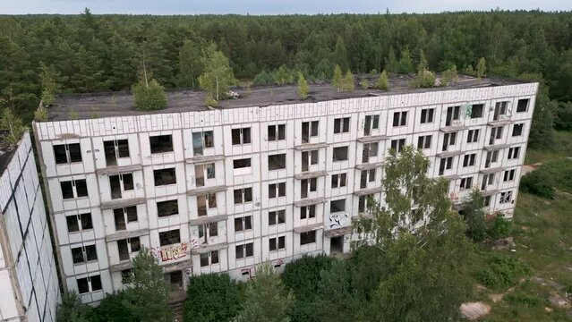 Irbene, Latvia - Ascending drone flight over an old soviet panel building in the ghost town Irbene with missing windows in a lost udssr settlement for military officers and their families - bird view