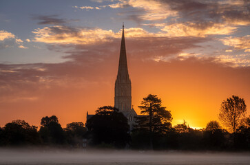 October misty morning sunrise behind Salisbury Cathedral from the Harnham water meadows Wilitshire...