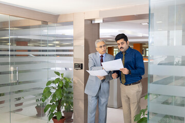 Two colleagues are checking some papers together in their office