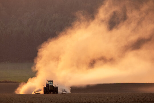 Tractor Tilling Empty Field Throwing up Dust at Sunset in Williamette Valley, Oregon, Autumn