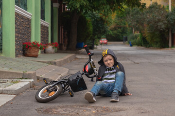 Kid hurts his forehead after falling off his bicycle. Child is learning to ride a bike