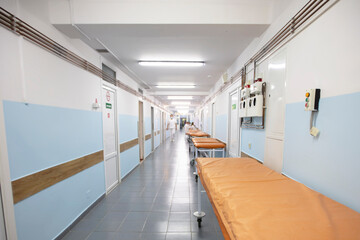 Long hospital corridor with gurneys without people.