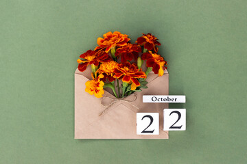 October 22. Bouquet of orange flower in craft envelope and calendar date on green background. Minimal concept Hello fall. Template for your design, greeting card