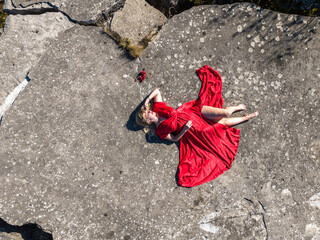 aerial view on girl in red dress on rock or concrete ruined structure