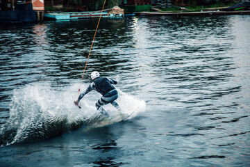 A guy in a yak suit at sunset jumps from a springboard on a wakeboard in an extreme park in Kiev. Ukraine.