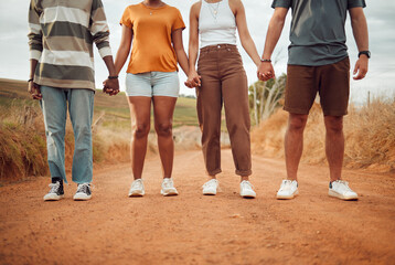 Legs, diversity and people holding hands together in solidarity, connection or support. Trust, friendship help and outdoor desert group, team or friends walk, travel or stand in countryside dirt road