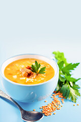 Pea lentil soup in a  bowl on a blue background. Copy space. Vertical template