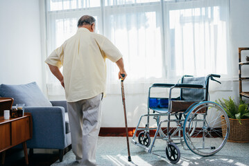 Asian senior old man with wheelchair walking with walker cane stick in nursing home, elderly mature disabled man patient, elderly health care concept.