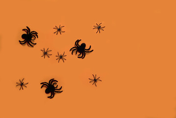 large and small plastic tarantula spiders on an orange background. Halloween concept. Background for a Halloween project