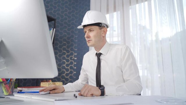 Engineer working with computer in his office.
The engineer in the white helmet is working hard.
