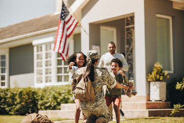 Servicewoman embracing her children on her homecoming - obrazy, fototapety, plakaty