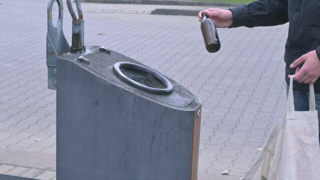 man throws a brown glass bottle into a glass container labeled "brown glass"