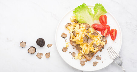 Black truffles gourmet brunch, breakfast. Scrambled eggs recipe with black truffles, bread tomatoes , white background. Internet banner, top view. Healthy recipe of Piedmont, Italy, Spain and France