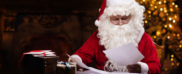 Workplace of Santa Claus. Cheerful Santa is reading letters from children while sitting at the...