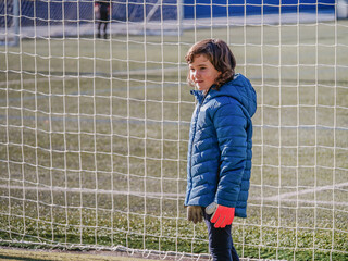 girl in front of a goal with goalkeeper gloves