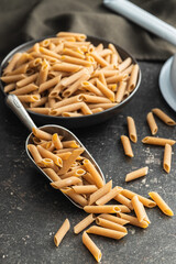 Uncooked whole grain pasta. Raw penne pasta in scoop.