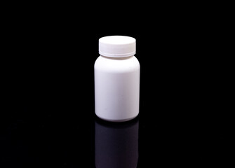 Medical pills in white jar on an isolated black background with reflection