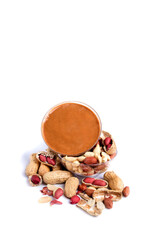 Peanut paste in a glass jar next to scattered peanuts. Isolated on a white background